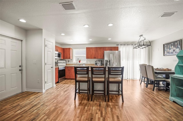 630 Mac Crillus Rd, Largo, FL 33770 - kitchen with stainless steel appliances, wood finished floors, light countertops, brown cabinets, and a textured ceiling