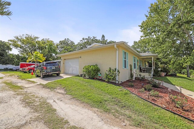 630 Mac Crillus Rd, Largo, FL 33770 - view of home's exterior with dirt driveway, stucco siding, a garage, a yard, and covered porch