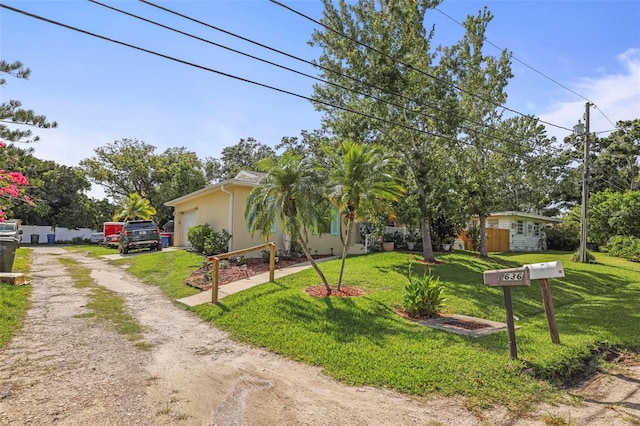 630 Mac Crillus Rd, Largo, FL 33770 - obstructed view of property with dirt driveway, a front yard, an attached garage, and stucco siding