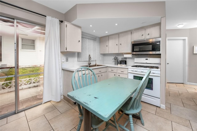 12400 Park Blvd Unit 417, Seminole, FL 33772 - kitchen with stainless steel microwave, white range with gas stovetop, light countertops, tasteful backsplash, and light tile patterned floors