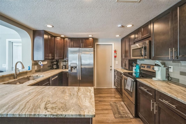 51 Cypress Dr, Palm Harbor, FL 34684 - kitchen featuring stainless steel appliances, a textured ceiling, dark brown cabinets, tasteful backsplash, and recessed lighting