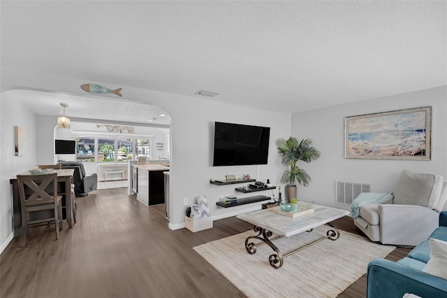 51 Cypress Dr, Palm Harbor, FL 34684 - living area with dark wood-type flooring, arched walkways, and a textured ceiling