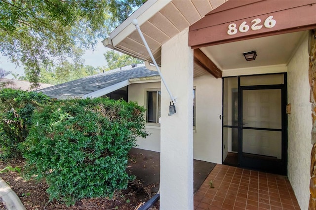 8626 Woodbridge Dr, New Port Richey, FL 34655 - view of exterior entry featuring a shingled roof and stucco siding