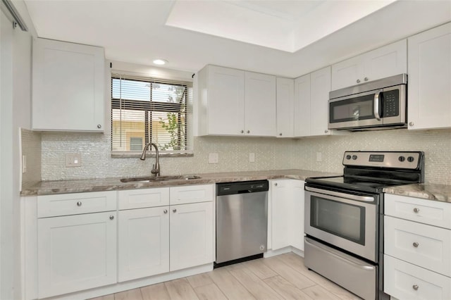 8626 Woodbridge Dr, New Port Richey, FL 34655 - kitchen featuring appliances with stainless steel finishes, white cabinetry, light stone counters, decorative backsplash, and recessed lighting