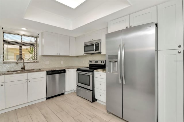 8626 Woodbridge Dr, New Port Richey, FL 34655 - kitchen featuring stainless steel appliances, a raised ceiling, white cabinets, backsplash, and light stone countertops