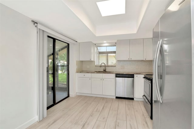 8626 Woodbridge Dr, New Port Richey, FL 34655 - kitchen with stainless steel appliances, backsplash, light wood-type flooring, a tray ceiling, and white cabinets