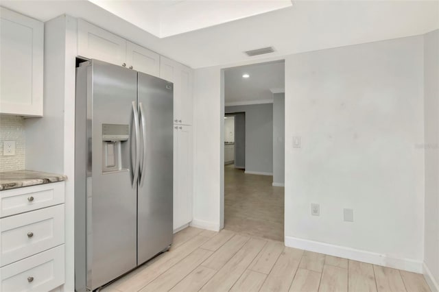8626 Woodbridge Dr, New Port Richey, FL 34655 - kitchen featuring stainless steel fridge with ice dispenser, light wood finished floors, white cabinetry, tasteful backsplash, and light stone countertops