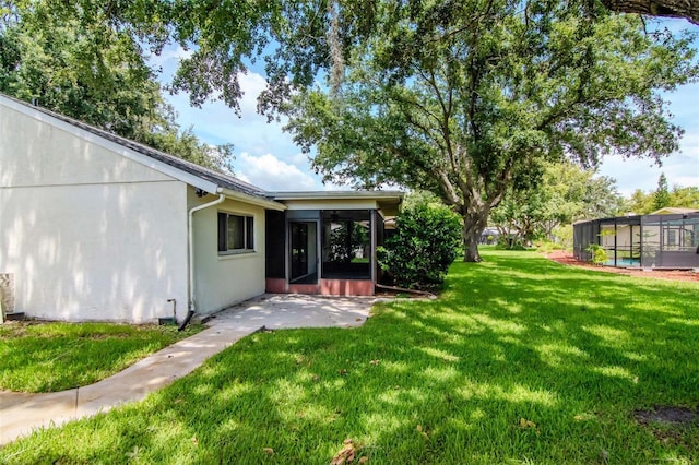 8626 Woodbridge Dr, New Port Richey, FL 34655 - view of green lawn featuring a sunroom and a patio area