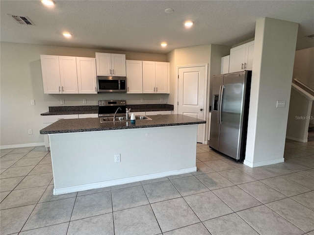 4448 Globe Thistle, Tampa, FL 33619 - kitchen with stainless steel appliances, white cabinets, an island with sink, dark stone counters, and recessed lighting