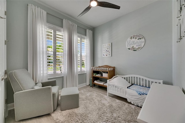 7420 Paradiso Dr, Apollo Beach, FL 33572 - bedroom featuring wood finished floors, a ceiling fan, and a nursery area