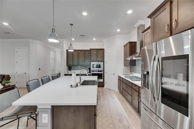 7420 Paradiso Dr, Apollo Beach, FL 33572 - kitchen with appliances with stainless steel finishes, ornamental molding, tasteful backsplash, light wood-type flooring, and a kitchen island with sink