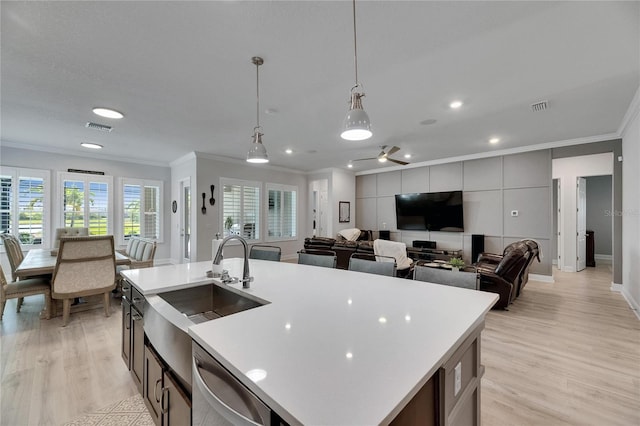 7420 Paradiso Dr, Apollo Beach, FL 33572 - kitchen featuring crown molding, light countertops, open floor plan, light wood-style floors, and decorative light fixtures