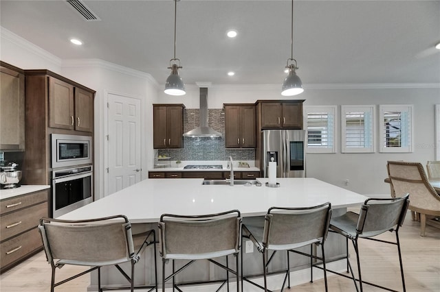 7420 Paradiso Dr, Apollo Beach, FL 33572 - kitchen with appliances with stainless steel finishes, wall chimney exhaust hood, a center island with sink, tasteful backsplash, and light countertops