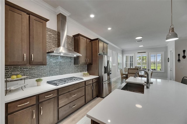 7420 Paradiso Dr, Apollo Beach, FL 33572 - kitchen featuring stainless steel appliances, wall chimney exhaust hood, crown molding, light countertops, and light wood-type flooring