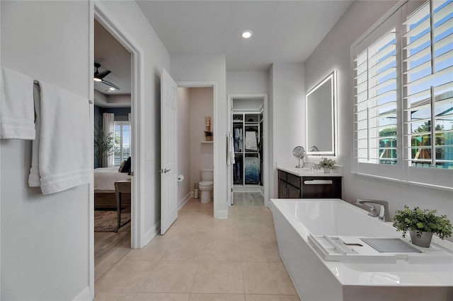 7420 Paradiso Dr, Apollo Beach, FL 33572 - ensuite bathroom featuring vanity, a soaking tub, tile patterned flooring, ceiling fan, and a spacious closet