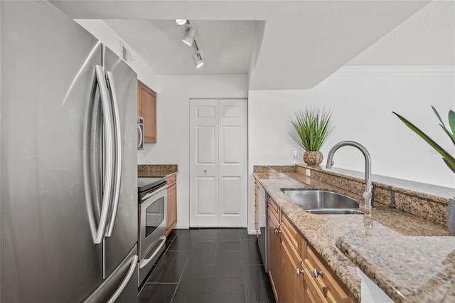 2400 Feather Sound Dr Unit 528, Clearwater, FL 33762 - kitchen featuring appliances with stainless steel finishes, brown cabinetry, track lighting, light stone countertops, and dark tile patterned flooring
