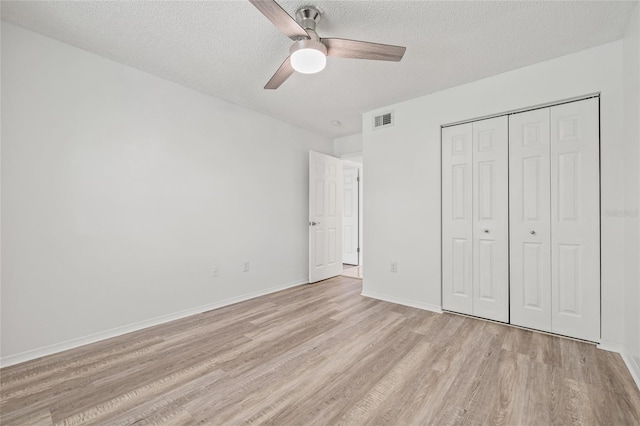 2400 Feather Sound Dr Unit 528, Clearwater, FL 33762 - unfurnished bedroom with light wood-style flooring, a textured ceiling, a closet, and a ceiling fan