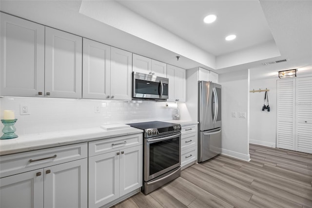 6372 Palma Del Mar Blvd S Unit 601, Saint Petersburg, FL 33715 - kitchen with appliances with stainless steel finishes, a tray ceiling, backsplash, white cabinetry, and recessed lighting