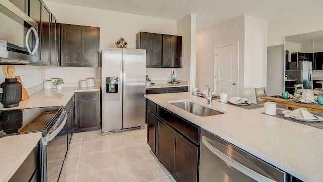 583 Mangrove Shade Cir, Apollo Beach, FL 33572 - kitchen featuring appliances with stainless steel finishes, a sink, light tile patterned flooring, and dark brown cabinetry