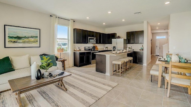 577 Mangrove Shade Cir, Apollo Beach, FL 33572 - kitchen featuring appliances with stainless steel finishes, recessed lighting, a breakfast bar area, a center island with sink, and light countertops