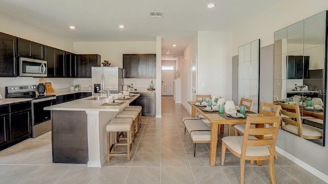 577 Mangrove Shade Cir, Apollo Beach, FL 33572 - kitchen with stainless steel appliances, a sink, a kitchen breakfast bar, a kitchen island with sink, and light tile patterned floors