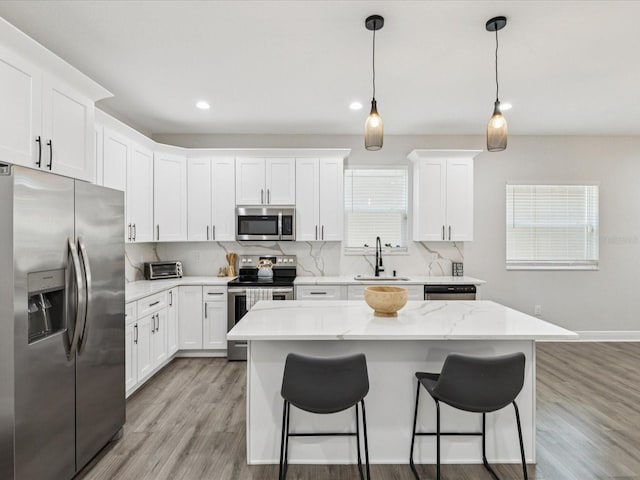 2809 N 21st St, Tampa, FL 33605 - kitchen with appliances with stainless steel finishes, a breakfast bar, decorative backsplash, white cabinetry, and light wood-style flooring