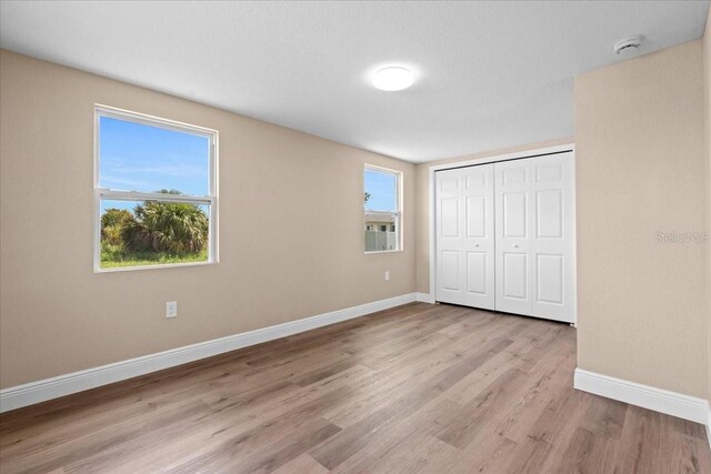 21536 Holdern Ave, Port Charlotte, FL 33952 - unfurnished bedroom featuring wood finished floors, baseboards, and a closet