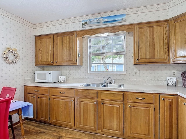 5755 Yorkshire Dr, Zephyrhills, FL 33542 - kitchen featuring white microwave, wallpapered walls, brown cabinets, wood finished floors, and light countertops