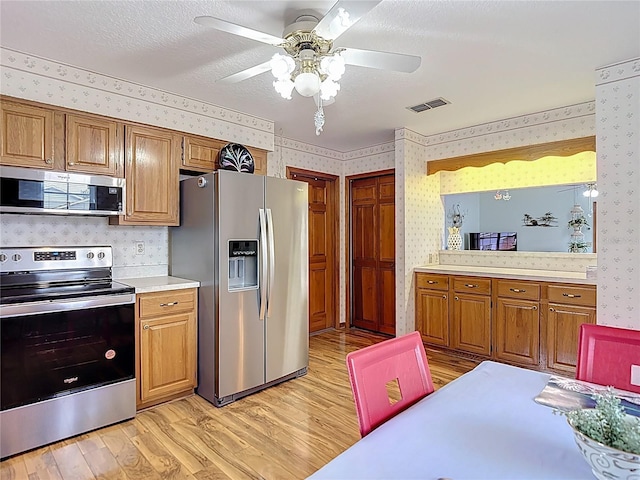 5755 Yorkshire Dr, Zephyrhills, FL 33542 - kitchen featuring appliances with stainless steel finishes, wallpapered walls, light wood-style floors, light countertops, and a ceiling fan