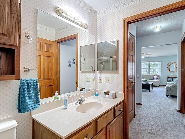 5755 Yorkshire Dr, Zephyrhills, FL 33542 - ensuite bathroom with vanity, wallpapered walls, a shower with shower door, a textured ceiling, and a ceiling fan