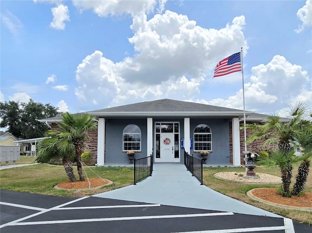 5755 Yorkshire Dr, Zephyrhills, FL 33542 - view of front of house featuring stucco siding, covered porch, a front lawn, and a shingled roof