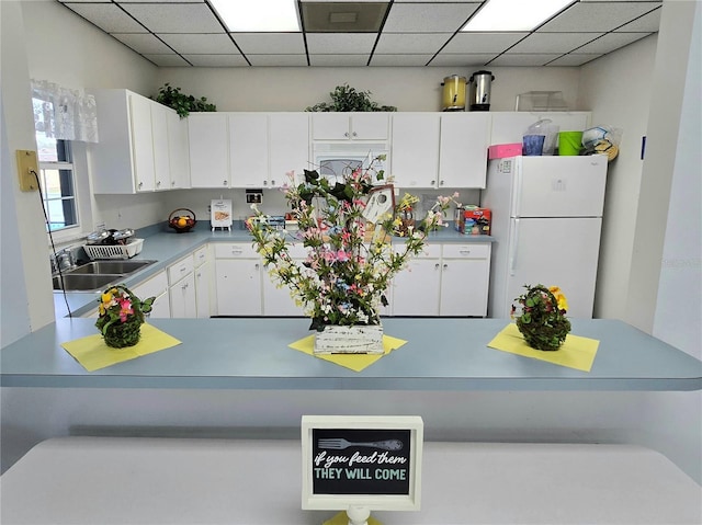 5755 Yorkshire Dr, Zephyrhills, FL 33542 - kitchen with freestanding refrigerator, white cabinets, a drop ceiling, and light countertops