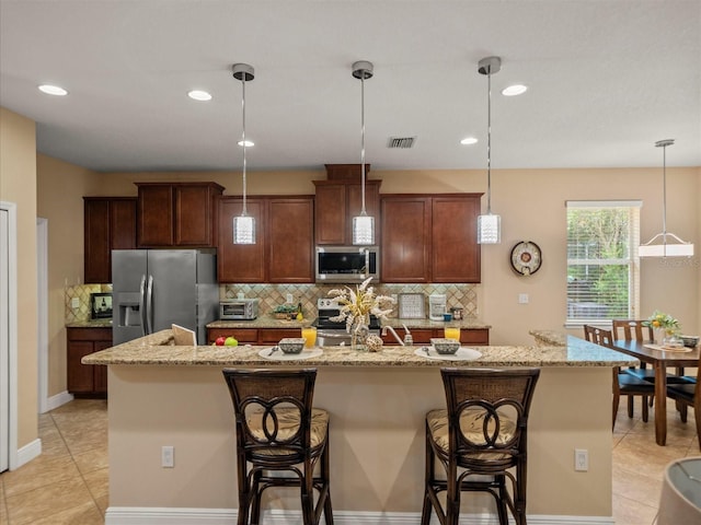 27546 Stonecreek Way, Wesley Chapel, FL 33544 - kitchen with appliances with stainless steel finishes, a center island with sink, backsplash, a breakfast bar, and recessed lighting