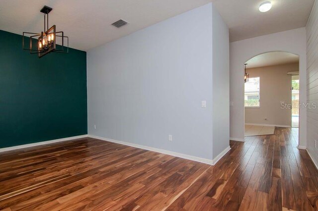 5916 Tulip Flower Dr, Riverview, FL 33578 - spare room with arched walkways, wood finished floors, and a chandelier