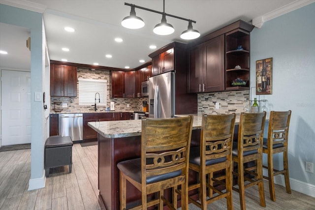 1230 Gulf Blvd Unit 304, Clearwater, FL 33767 - kitchen featuring appliances with stainless steel finishes, crown molding, a peninsula, light wood-type flooring, and decorative backsplash