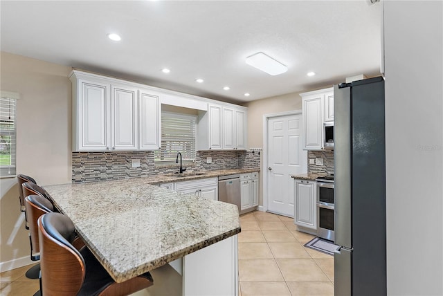 11029 Clay Pit Rd, Tampa, FL 33610 - kitchen featuring stainless steel appliances, a peninsula, a breakfast bar, a sink, and decorative backsplash
