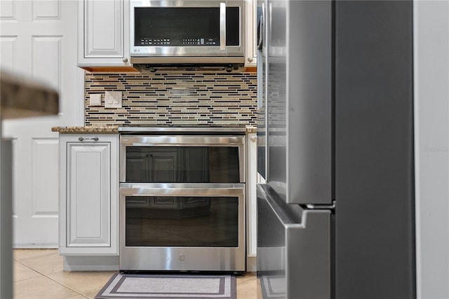 11029 Clay Pit Rd, Tampa, FL 33610 - kitchen view of appliances with stainless steel finishes, white cabinets, decorative backsplash, and stone counters