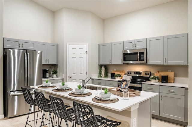 1201 Tidal St, Haines City, FL 33844 - kitchen featuring stainless steel appliances, gray cabinets, a towering ceiling, a kitchen bar, and light countertops
