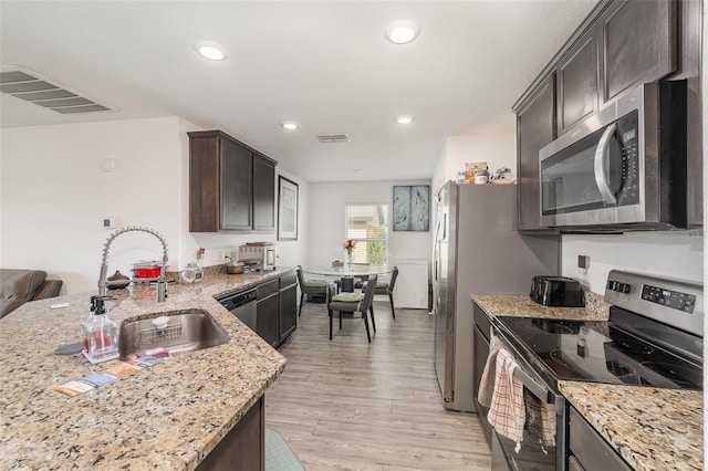 1741 Canaan Loop, Dundee, FL 33838 - kitchen with stainless steel appliances, dark brown cabinets, light stone counters, light wood-style floors, and recessed lighting