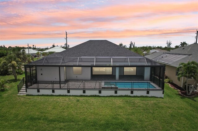 15218 Appleton Blvd, Port Charlotte, FL 33981 - back of house at dusk featuring a yard, an outdoor pool, a patio area, and glass enclosure