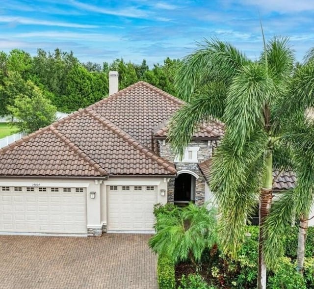 14807 Bowfin Ter, Lakewood Ranch, FL 34202 - mediterranean / spanish house featuring stone siding, an attached garage, a tiled roof, and driveway