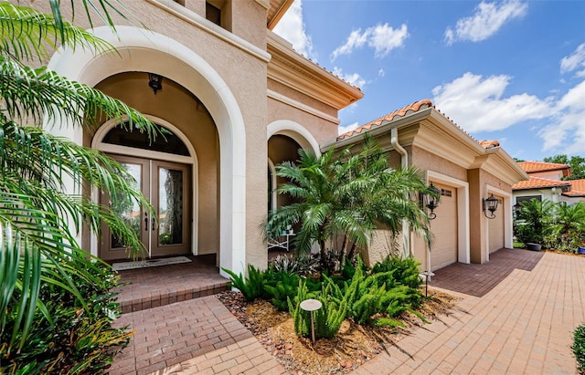 1012 Tuscany Dr, Trinity, FL 34655 - entrance to property with stucco siding, an attached garage, french doors, driveway, and a tiled roof