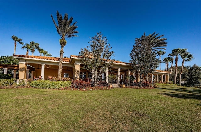 1012 Tuscany Dr, Trinity, FL 34655 - rear view of property featuring a lawn, a ceiling fan, a tiled roof, and stucco siding
