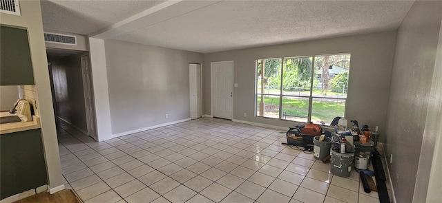 2503 Elm St, Seffner, FL 33584 - unfurnished living room featuring light tile patterned floors, a textured ceiling, baseboards, and a sink