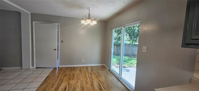 2503 Elm St, Seffner, FL 33584 - unfurnished dining area with a chandelier, a textured ceiling, light wood-style flooring, vaulted ceiling, and baseboards