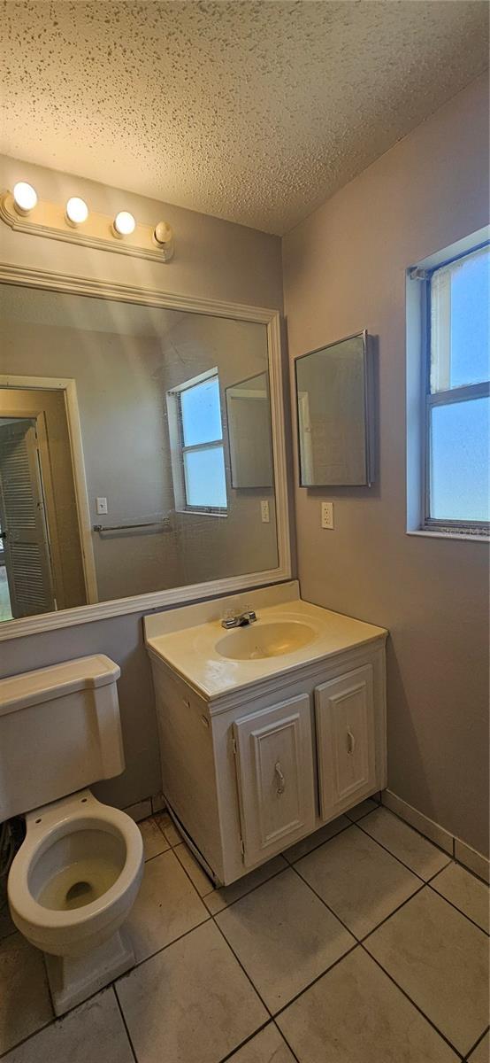 2503 Elm St, Seffner, FL 33584 - bathroom with tile patterned flooring, vanity, toilet, and a textured ceiling
