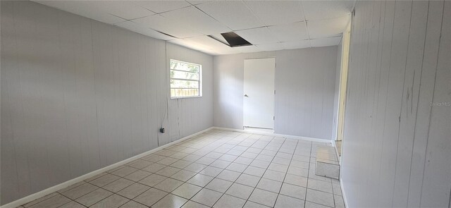 2503 Elm St, Seffner, FL 33584 - empty room featuring light tile patterned floors, wooden walls, baseboards, and a drop ceiling