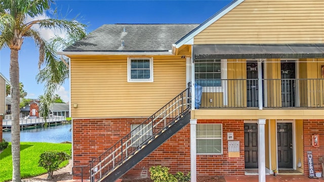 200 Country Club Dr Unit 202, Largo, FL 33771 - rear view of house with brick siding, a water view, stairs, and roof with shingles