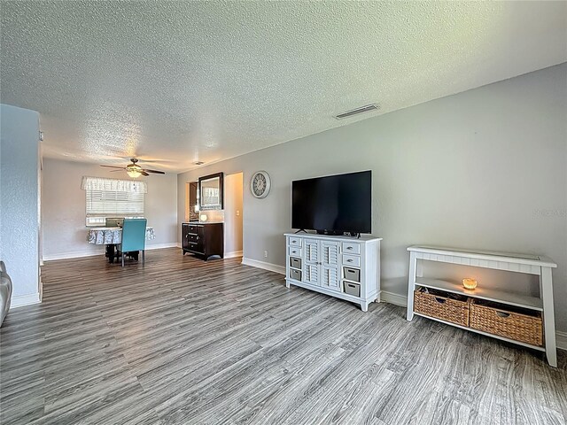 200 Country Club Dr Unit 202, Largo, FL 33771 - living room featuring wood finished floors, a textured ceiling, a ceiling fan, and baseboards