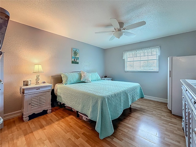 200 Country Club Dr Unit 202, Largo, FL 33771 - bedroom with freestanding refrigerator, light wood-style floors, baseboards, a textured ceiling, and ceiling fan